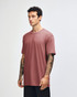 A side view of a woman wearing a rose pink unisex short sleeve T-shirt. The shirt has a simple design and a logo.