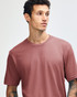 A unisex fine jersey short sleeve T-shirt in a muted red colour, paired with light blue oversized pants.