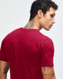 A maroon unisex fine jersey short sleeve t-shirt is displayed on a model wearing blue jeans. The shirt has a logo.