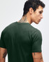 A green short sleeve t-shirt worn by a person, featuring a logo on the back.