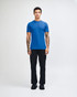 A blue short sleeve t-shirt displayed on a model wearing black pants, featuring a logo on the t-shirt.