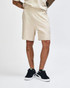 Beige unisex gym shorts with an elastic waistband and side pockets, worn with white sneakers and grey socks.