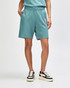 A pair of teal unisex gym shorts with an elastic waistband and side pockets, worn with white sneakers and socks.