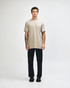 A model wearing an olive green unisex CVC short sleeve t-shirt and black cargo pants, featuring a logo.