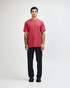 A unisex CVC short sleeve t-shirt in red, paired with black cargo pants. The model displays a casual pose.