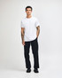 A young man wearing a plain white unisex short sleeve t-shirt and loose blue jeans, standing against a white background.