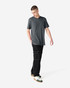 A unisex short sleeve T-shirt in grey paired with black cargo pants, featuring a simple design and a logo.