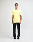 A man wearing a bright yellow unisex short sleeve t-shirt and black baggy pants, with sneakers.