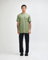 A model wearing a green unisex short sleeve T-shirt and black cargo pants, standing in a neutral setting.