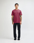 A model wearing a maroon unisex CVC short sleeve t-shirt paired with black trousers and shoes.