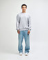 A grey unisex crewneck sweatshirt displayed on a model wearing black cargo pants and sneakers.