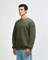 A unisex crewneck sweatshirt in green, featuring long sleeves and a relaxed fit, with a logo at the hem.