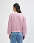 A women's crewneck sweatshirt in soft pink, featuring a relaxed fit and a branded label on the back.
