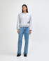 A grey women's crewneck sweatshirt with long sleeves, semi-fitted style, worn with light blue jeans.