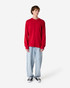 A red long sleeve t-shirt displayed on a model wearing loose-fitting light blue jeans and black sneakers.