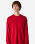 A model wearing a red long sleeve t-shirt, featuring a relaxed fit and crew neck. The shirt has a logo.