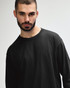 A model wearing a black long sleeve t-shirt made of ultra cotton, featuring a simple design and relaxed fit.