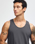 A unisex fine jersey tank in grey, featuring wide armholes and a simple design. The model is adjusting the tank.