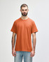 A man wearing a Gildan Heavy Cotton adult T-shirt in a vibrant orange colour, featuring a logo.