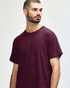 A maroon Gildan Heavy Cotton Adult T-Shirt displayed on a model with short, curly hair. The shirt has a logo.