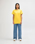 A yellow Gildan Heavy Cotton adult T-shirt worn by a male model, alongside black pants and sneakers.