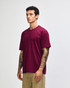 A maroon heavyweight t-shirt on a model, featuring a rounded neckline and short sleeves, with a logo present.