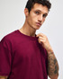 A maroon American Apparel Super Heavyweight T-Shirt displayed on a model with short hair and a neutral background.