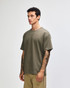 A green American Apparel super heavyweight t-shirt displayed on a model standing upright, featuring a round neckline.