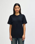 A model wearing a black Gildan Softstyle adult t-shirt paired with light blue jeans. The shirt has a logo.