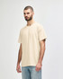 A beige Gildan Softstyle adult T-shirt features a relaxed fit and short sleeves, paired with light blue jeans.