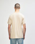 A neutral beige adult t-shirt featuring short sleeves and a simple design with a logo on the back.