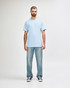 A plain light blue Gildan Softstyle adult T-shirt worn with straight-leg jeans and white shoes, featuring a logo.