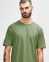 A model wearing a short-sleeved, olive green Gildan Softstyle adult t-shirt. The shirt features a simple design and a logo.