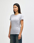 A grey Gildan Softstyle ladies' T-shirt, featured on a model, styled with blue jeans. The shirt has a logo.