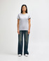 A grey ladies' t-shirt is worn with blue jeans and white sneakers, showcasing a casual outfit. The t-shirt has a logo.