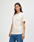 A cream-coloured American Apparel Tri-Blend T-shirt displayed on a model with straight brown hair, paired with blue jeans.