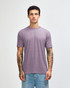 A man wearing a purple American Apparel tri-blend T-shirt paired with light blue jeans, featuring visible tattoos on his arms.
