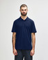 A model wearing a navy blue Gildan Softstyle Adult Double Pique Polo. The polo has a logo on it.