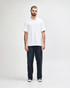 A model wearing a white Gildan Softstyle Adult Double Pique Polo paired with black pants and sneakers.