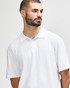 A white Gildan Softstyle adult double pique polo shirt on a model, featuring a collar and three buttons.