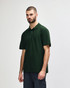 A model wearing a dark green polo shirt with a classic collar and short sleeves, featuring a logo.