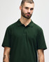 A model wearing a dark green Gildan Softstyle Adult Double Pique Polo with a three-button placket and collar.