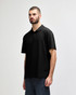 A model wearing a black Gildan Softstyle Adult Double Pique Polo, featuring a classic polo collar and short sleeves.