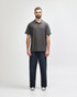 A grey Gildan Softstyle Adult Double Pique Polo is worn by a model, paired with light blue jeans. The polo features a logo.