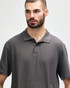 A model wearing a dark grey Gildan Softstyle Adult Double Pique Polo, featuring a classic collar and three-button placket.