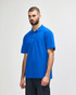 A man models a royal blue Gildan Softstyle Adult Double Pique Polo, featuring a logo on the left side.