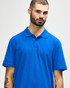 A blue Gildan Softstyle adult double pique polo shirt on a model, featuring a collar and buttons, with a logo.