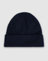 A navy blue watch cap featuring a folded cuff and a textured knit design. It includes a logo.