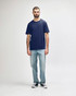 A man wearing a navy Gildan Softstyle adult midweight T-shirt and light blue jeans, standing against a plain background.