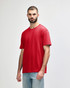 A red midweight t-shirt on a model, featuring a simple design and a logo on the shirt.